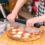 Paleta de bambú Ooni 12 pulgadas con pizza recién horneada y cortador de cuchilla