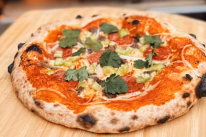 Pizza dieciochera con salsa de pimientos rojos, chorizo, carne, cebolla, ají verde y cilantro, receta típica para Fiestas Patrias en Chile.